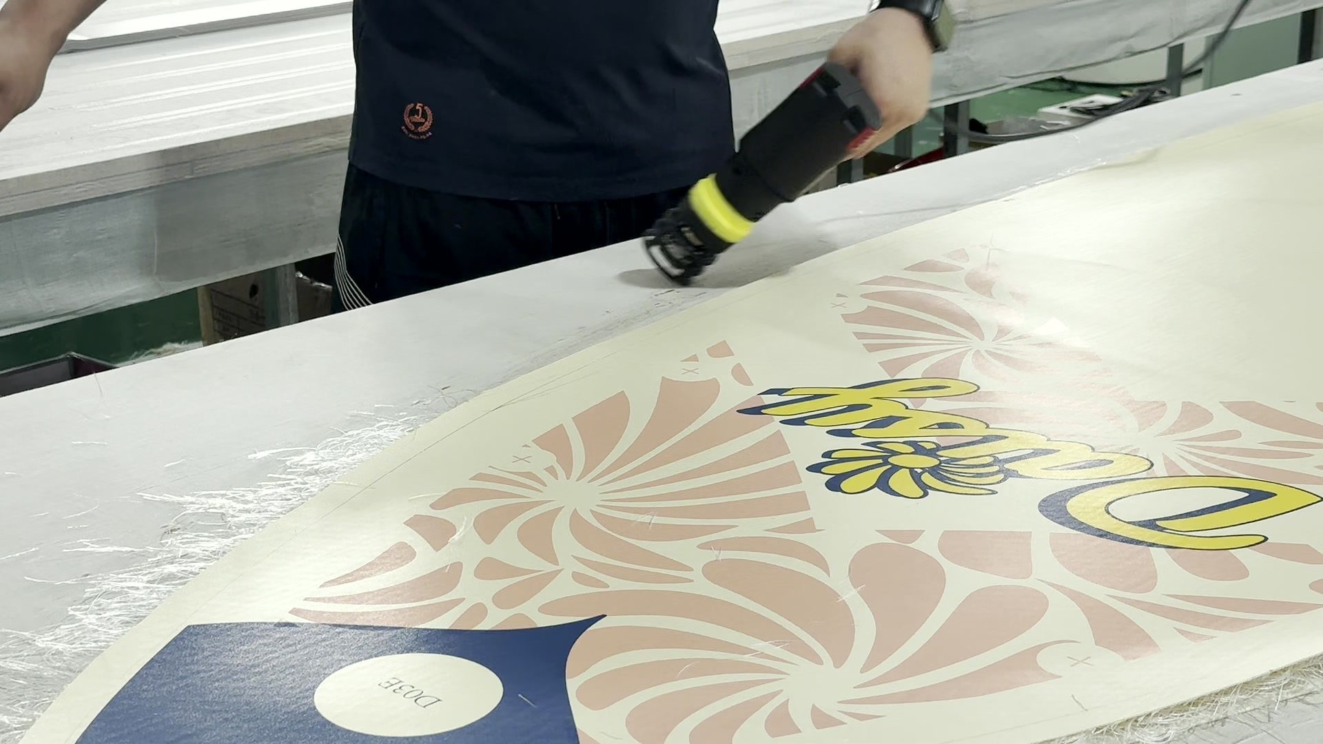 Hand-held tool passing over a printed deck sheet on a work table.