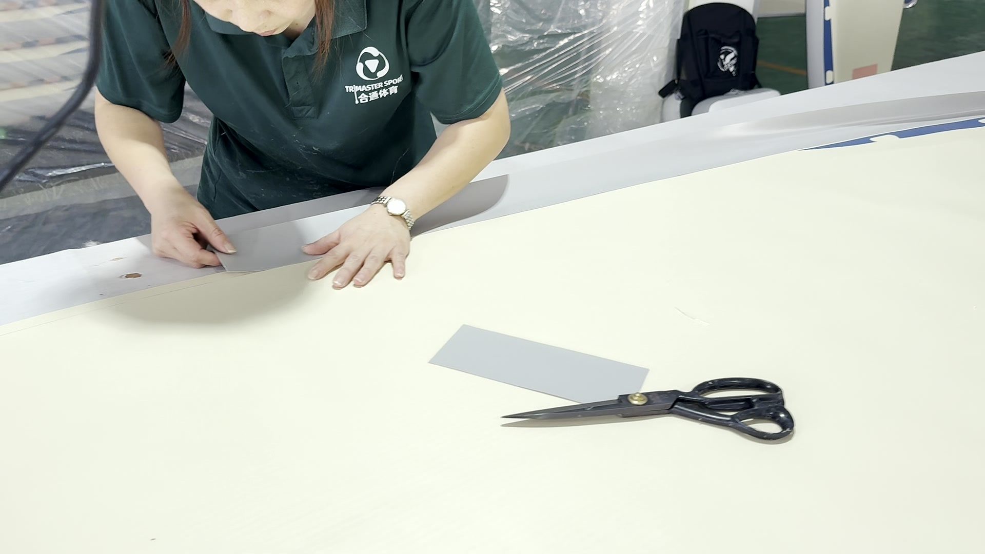 Hands working along a strip of sheet stock with scissors on the bench.