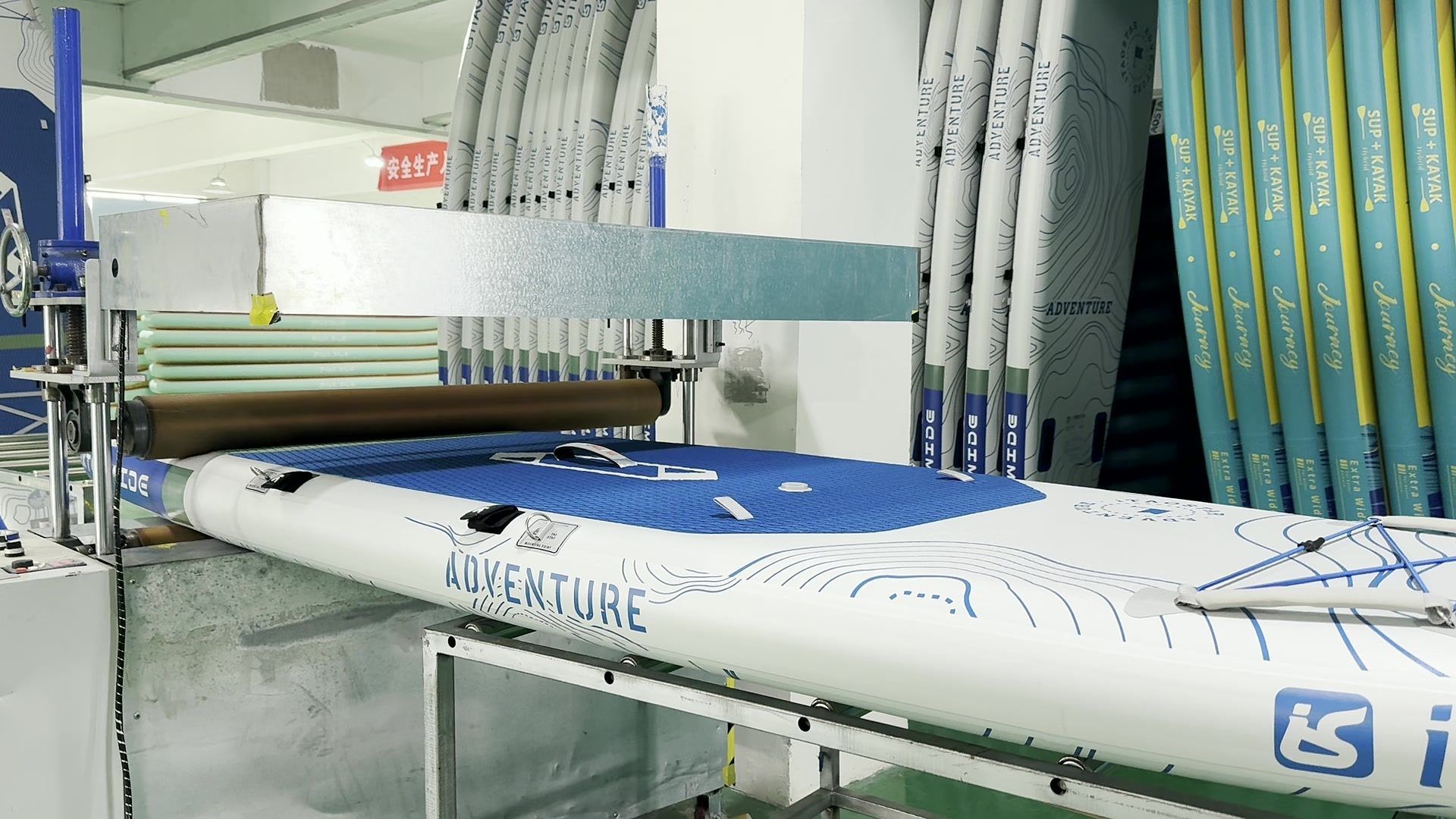 Mechanical roller pressing a paddle board deck.