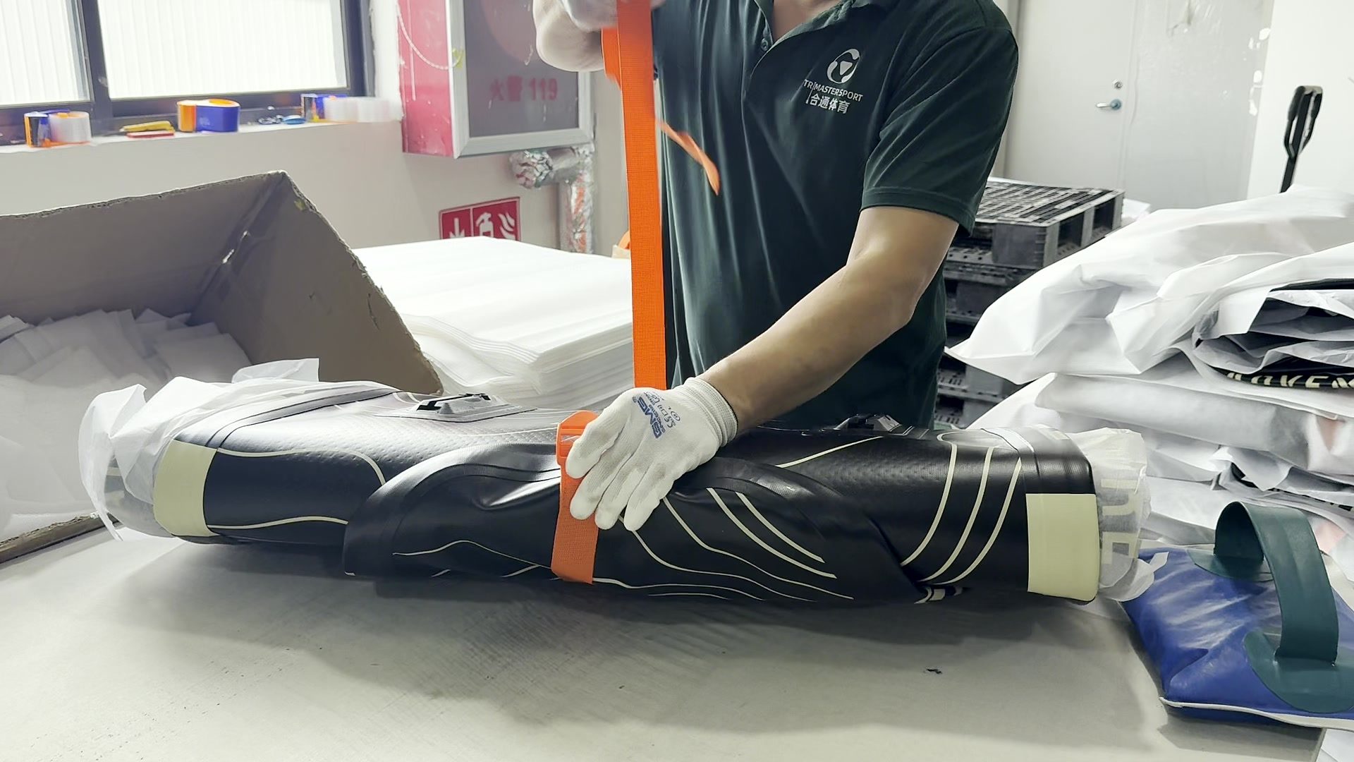 Worker folding and bagging a finished paddle board.