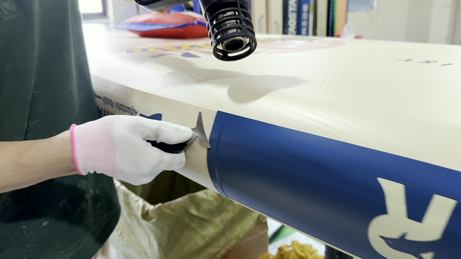 Gloved hand setting a patch at the rail corner of a board.