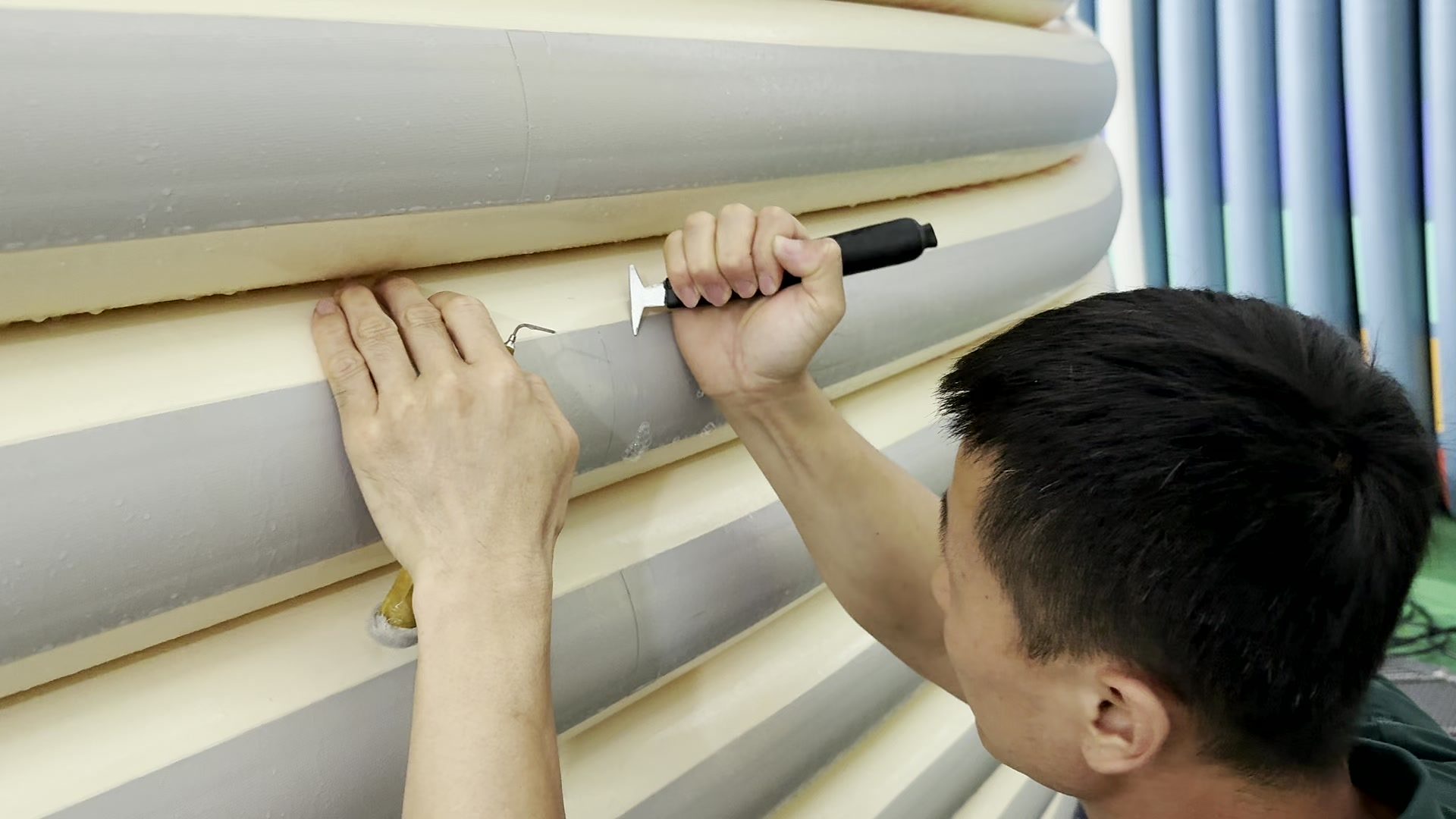 Worker cutting along the seam of a stacked board.