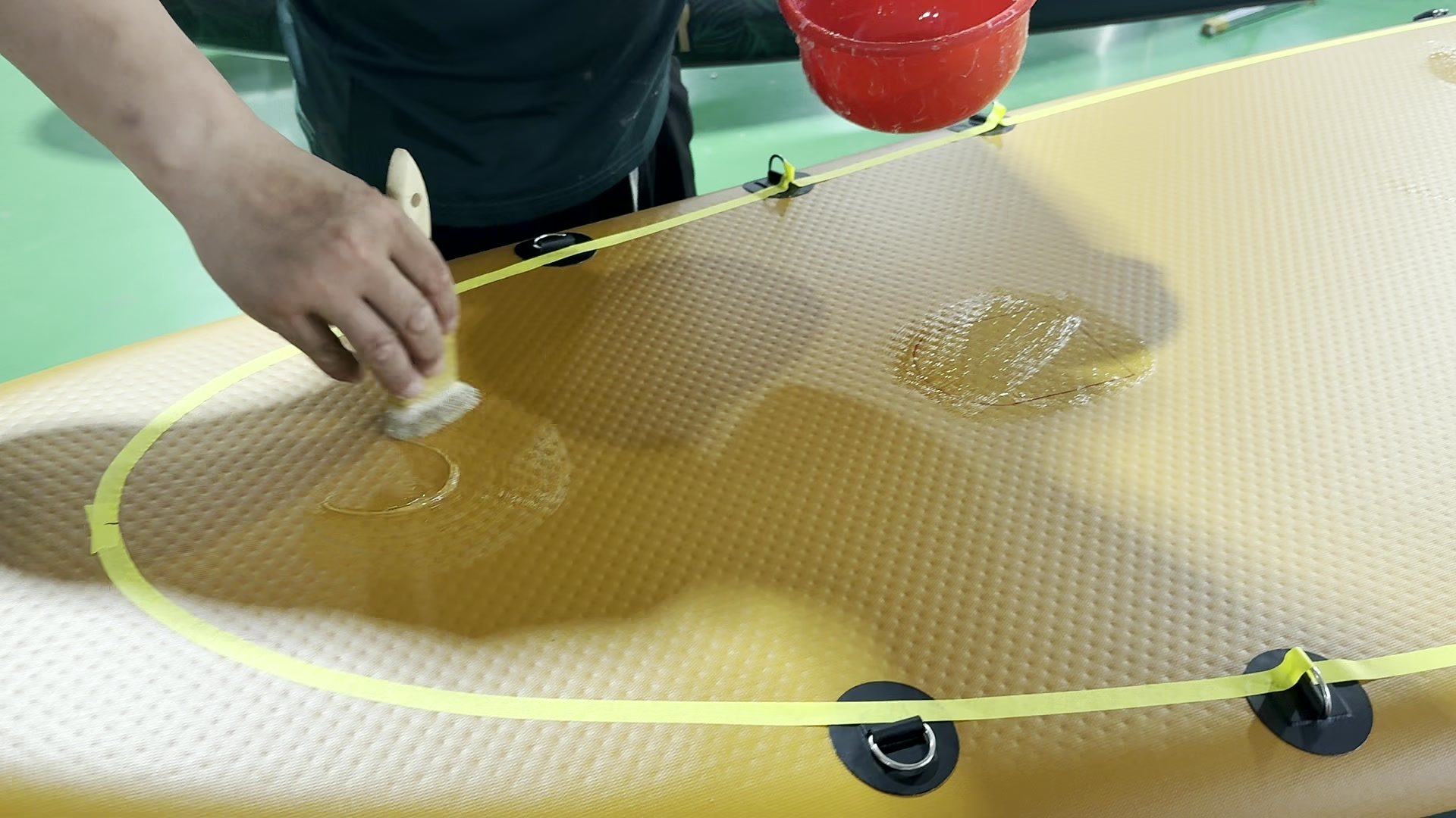 Masking tape outlining a glue area on a paddle board deck.
