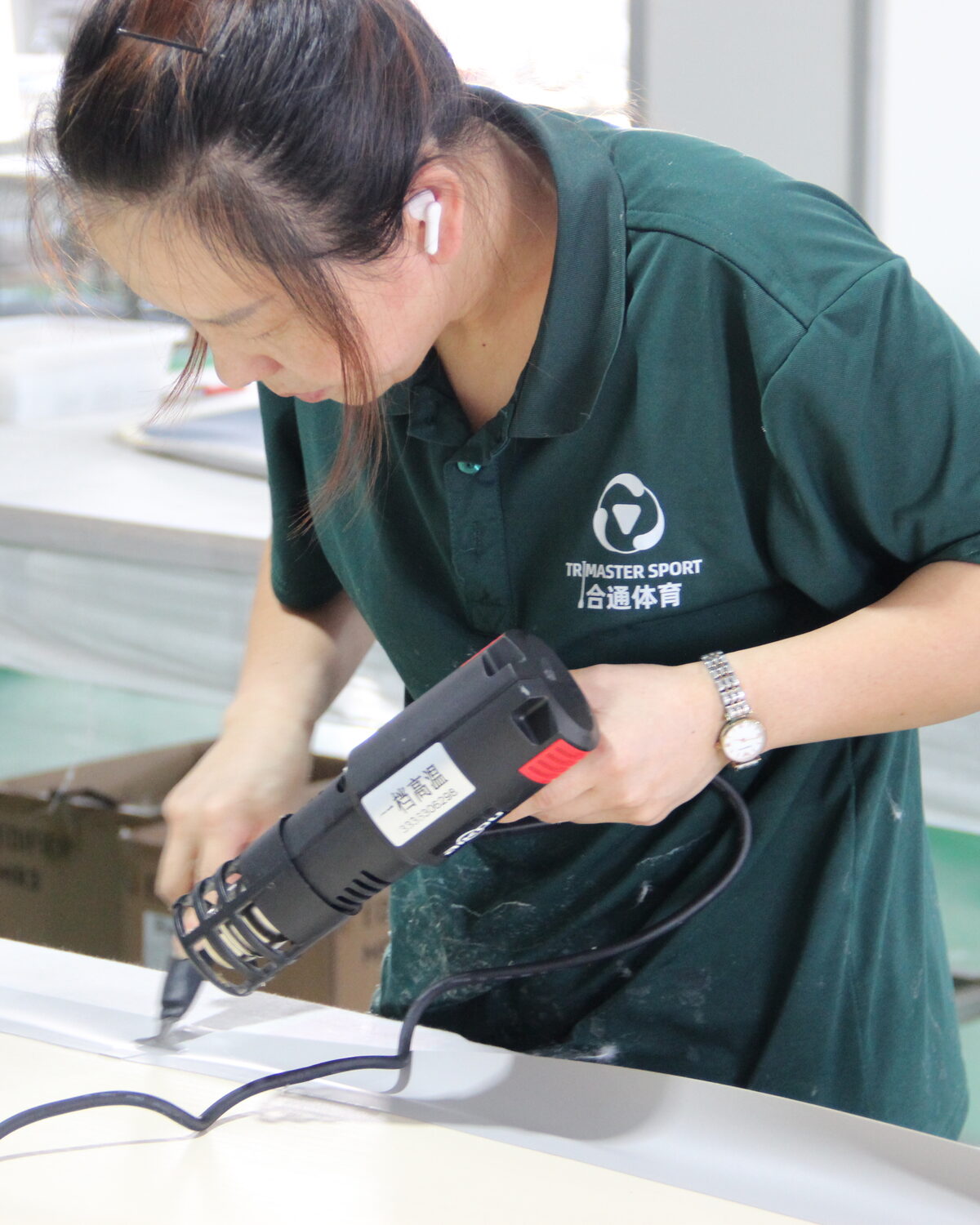 An operator working a graphic onto a board deck with a heat tool.