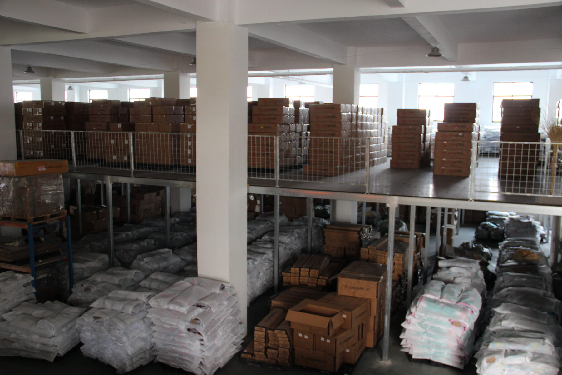 Storage racks holding wrapped boards and cartons in the factory warehouse.